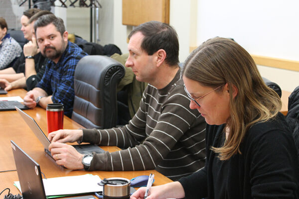 Eric Buxton and others sitting at a table during a meeting