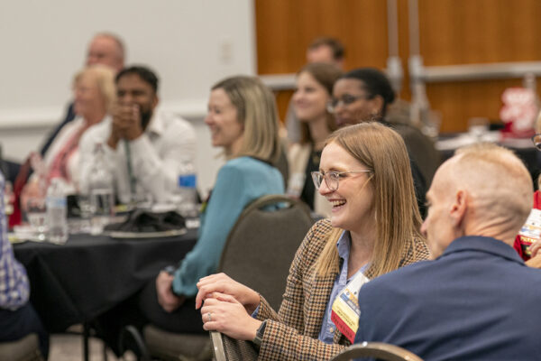 Attendees smiling and laughing while watching the stage
