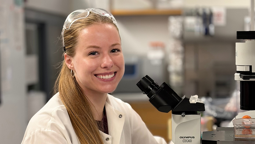 Allie Barrett in a lab working with a microscope