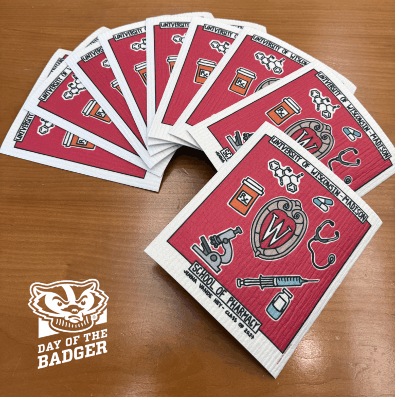 A stack of Swedish dish cloths that include the W crest for Wisconsin and illustrations related to pharmacy, including a syringe, microscope, stethoscope, and prescription bottle