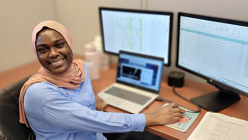 Fatima Abdul Rasheed smiles while working on a computer