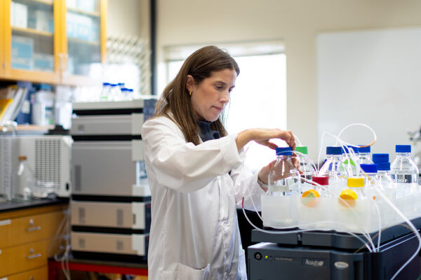 Molly Petterli Hahn is working with bottles with colorful red, yellow, and blue lids in a lab setting