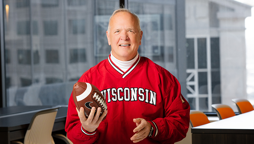 Tom McCourt wearing Badger gear and holding a football