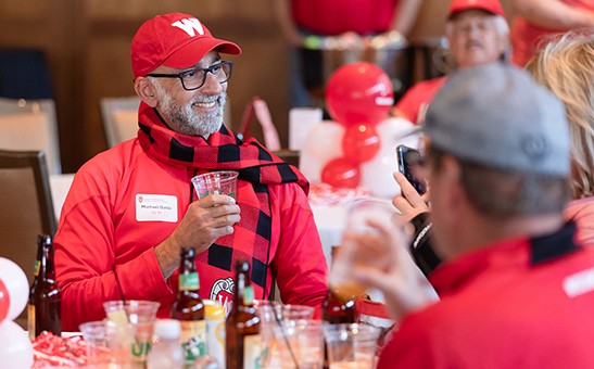 Alum Michael Gallo (BS '91) enjoys a drink with friends, draped in Badger gear.