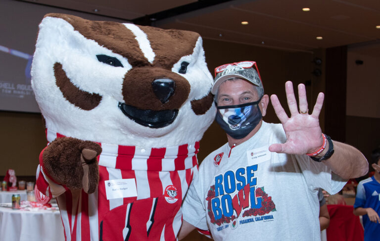 Bucky Badger and a School of Pharmacy alum waving at the camera during the 2021 Tailgate