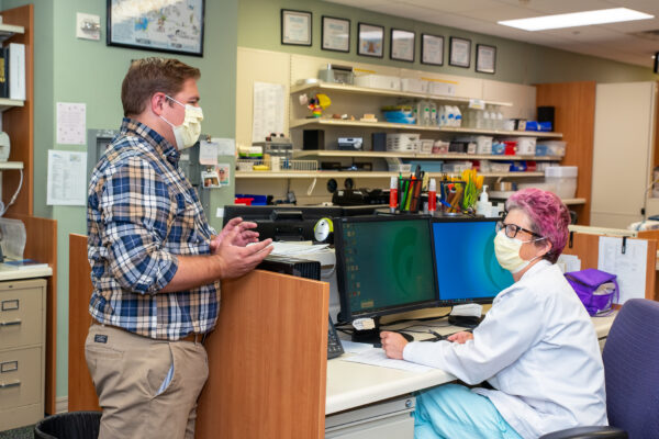 Alum Tyler Prickette (left) speaking to a colleague at the FortHealth Care Pharmacy.