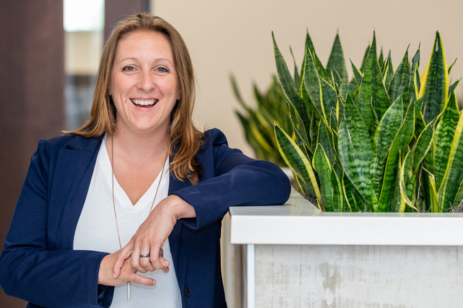Sharon Faust smiles next to a plant