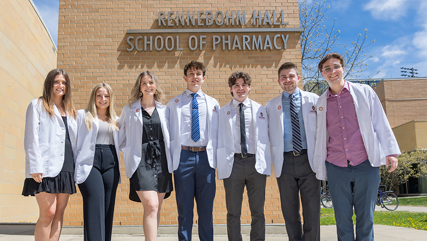 A group of PharmD students in white coats outside of Rennebohm Hall