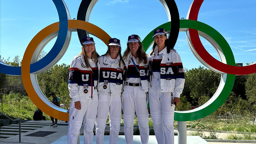 Sophia Vitas poses with teammates in front of the Olympic rings